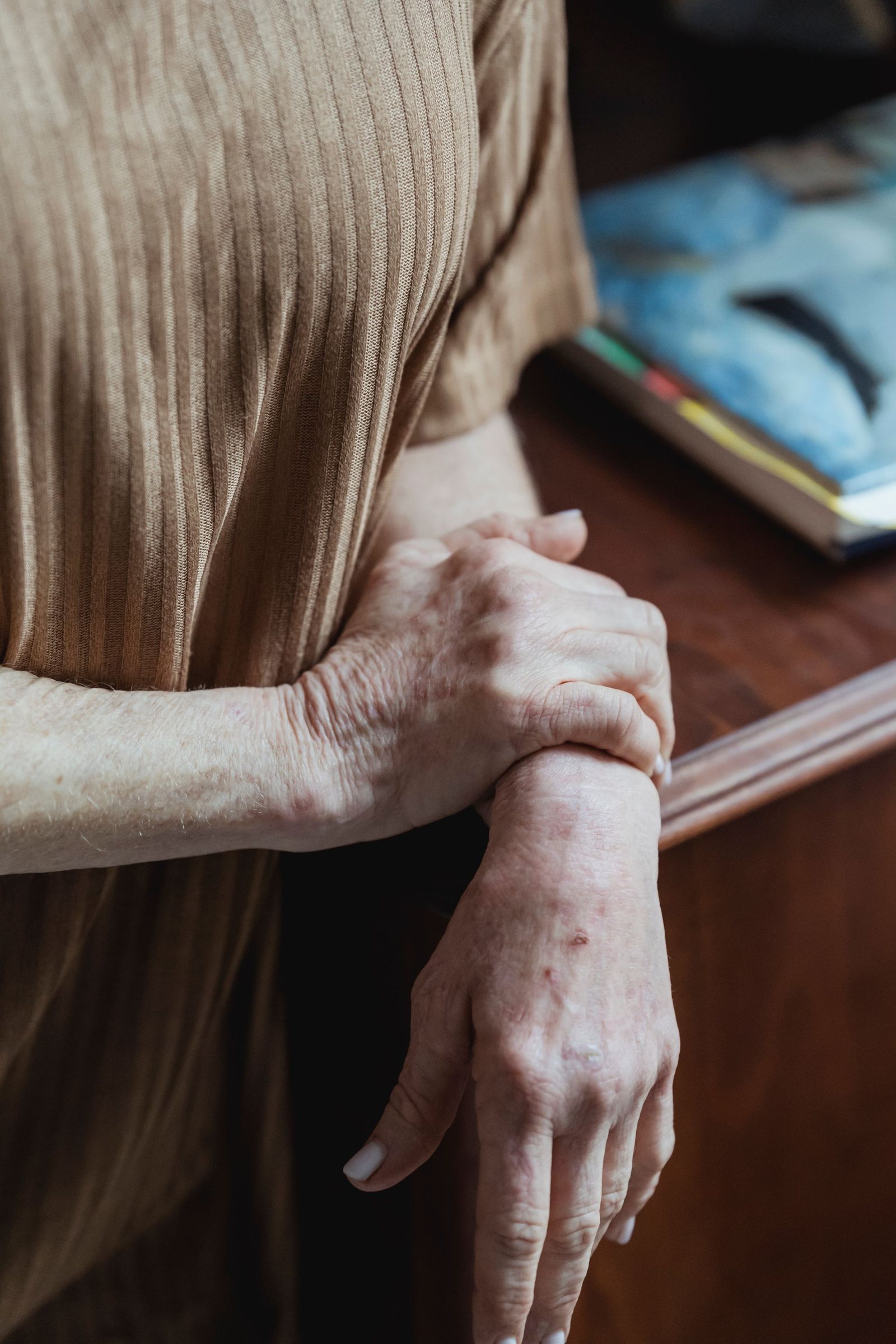 Mains jointes d'une femme agee, dans une lumiere douce et chaleureuse