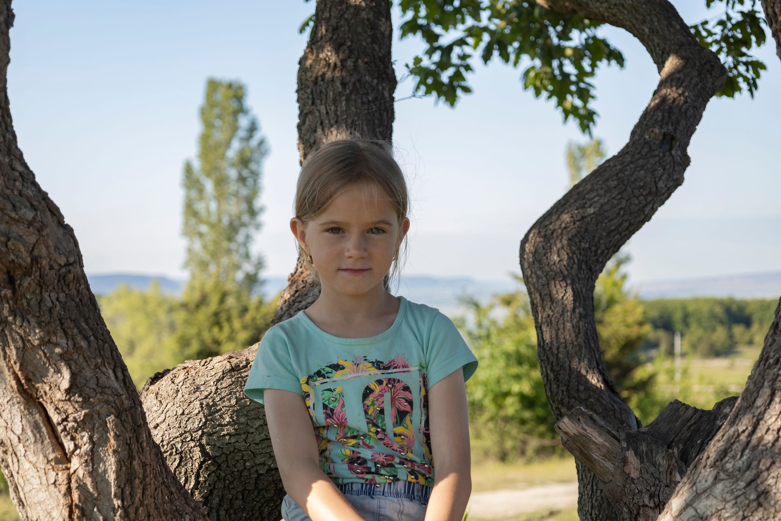 Jeune enfant assise paisiblement dans un arbre, au calme dans la nature