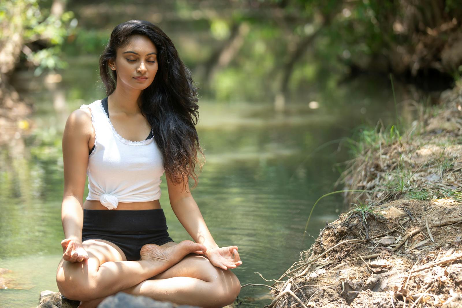 Femme en meditation au bord d'une riviere paisible