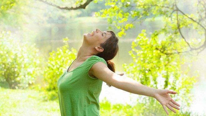 Une femme apaisée, bras ouverts dans la nature